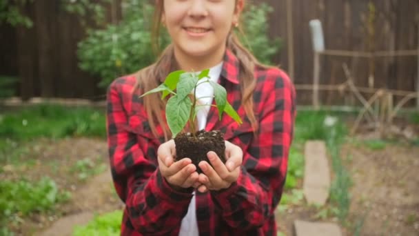 Slow motion video of smiling young woman posing with seedling at garden — Stock Video