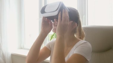 Sandalyede oturan ve Vr kulaklık kullanarak heyecanlı genç kadın portresi. 4 k çekim görüntüleri