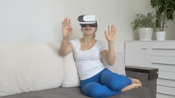 Jovem feliz vestindo fone de ouvido realidade virtual sentado no sofá. Filmagem a 4K — Vídeo de Stock