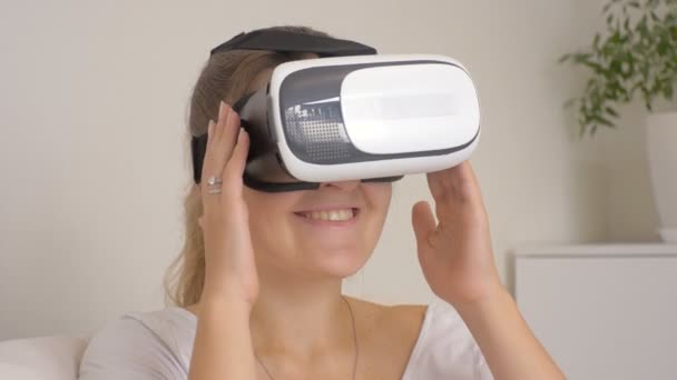 Портрет улыбающейся девушки, использующей гарнитуру виртуальной реальности дома. Съемка на 4k — стоковое видео