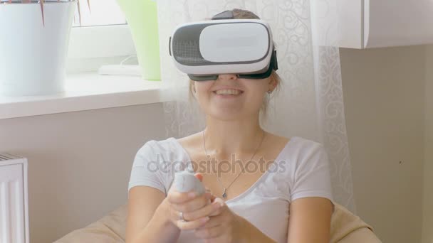 Портрет красивої усміхненої жінки в гарнітурі віртуальної реальності, яка дивиться 3d фільм і використовує пульт дистанційного керування. Знімок відео на 4k — стокове відео