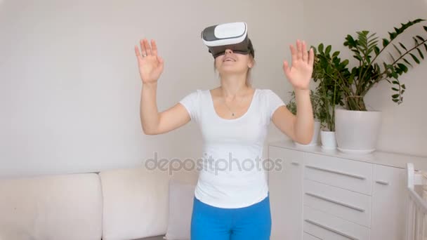 Neşeli ve hayret odada yürürken sanal gerçeklik kulaklık giyen kadın. 4 k çekim görüntüleri — Stok video
