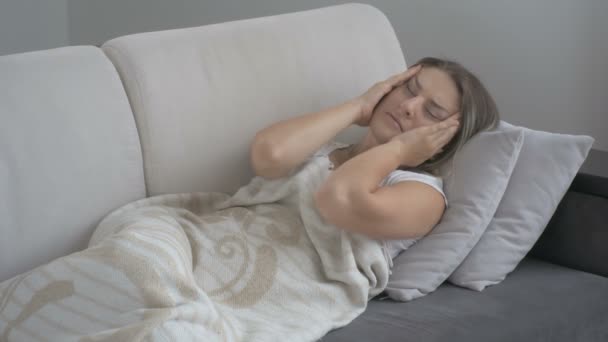 Junge Frau mit Migräne auf Couch im Wohnzimmer liegend. Aufnahmen in 4k — Stockvideo