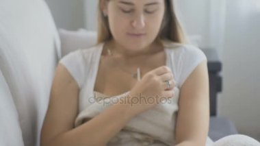 Genç kadın kanepe oturma odasında sıcaklık ölçme üzgün
