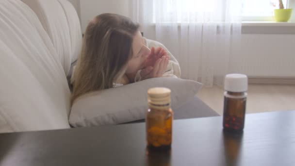 Młoda kobieta chory dostał grypy i biorąc pigułki w butelce z tabeli w salonie — Wideo stockowe