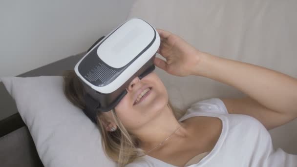 Primer plano de la feliz mujer sonriente acostada en el sofá y usando auriculares VR. Filmación en resolución 4K — Vídeos de Stock