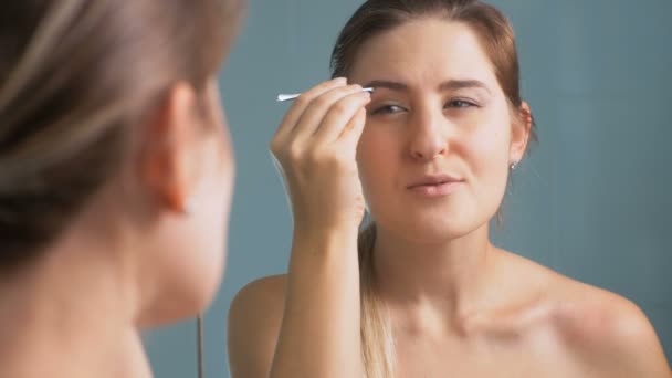 4K gros plans de belle femme brune façonnant ses sourcils au miroir — Video