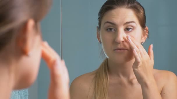 4K крупным планом, где женщина проверяет лицо на наличие морщин в ванной — стоковое видео
