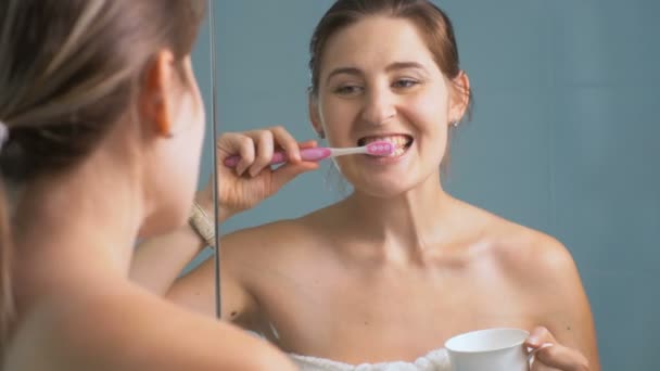 Imágenes 4K de mujeres jóvenes cepillándose los dientes y mirando el reloj de pulsera — Vídeo de stock