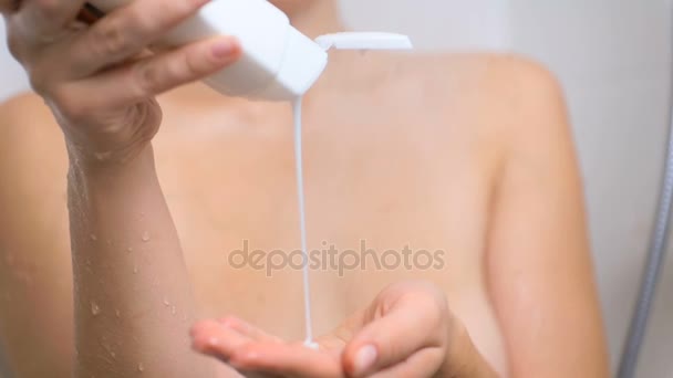 Closeup slow motion video of young woman pouring shampoo on hand at shower — Stockvideo