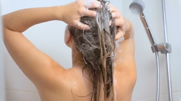 Vista trasera en cámara lenta de la sexy morena lavando el cabello con champú en la ducha — Vídeo de stock