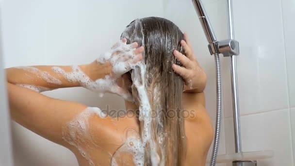 Slow motion footage of brunette woman washing off shampoo from hair — Stock Video