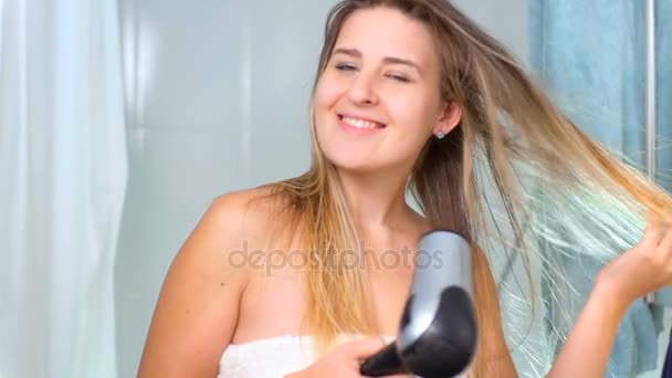Αργή κίνηση μήκος σε πόδηα του όμορφη γυναίκα με μακριά μαλλιά χρησιμοποιώντας στεγνωτήρα μαλλιών στο μπάνιο — Αρχείο Βίντεο
