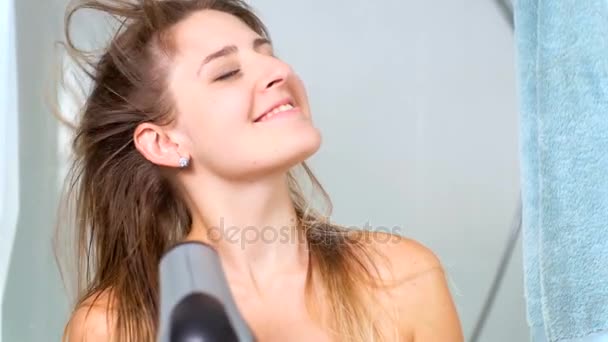 Повільний портрет красивої жінки, що сушить волосся з сушаркою — стокове відео