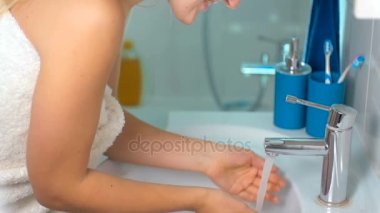 Su musluk ve banyo çamaşır yüze genç kadın ağır çekim görüntüleri açar