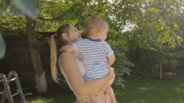 Mutlu genç kadın bebek oğlu orchard'ağacının altında sarılma