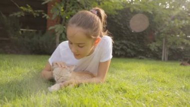 Dolly atış çim üzerinde yalan ve kırmızı kedi yavrusu sevecen tatlı kız