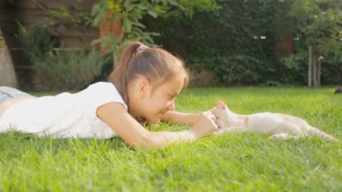 Sevimli kız arka bahçe ve sevecen kedi çimenlerin üzerinde rahatlatıcı