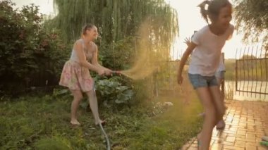 Bahçede oynayan ve hosepipe su ile yağmurlama mutlu aile