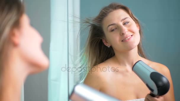 Mouvement lent de belle jeune femme séchant les cheveux au miroir — Video