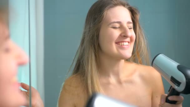 Rallentatore di felice donna bionda che canta asciugando i capelli allo specchio — Video Stock