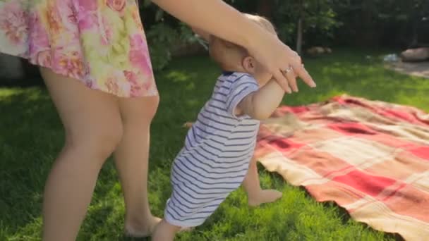 若い母親は裏庭の芝生の上の最初のステップの彼女の赤ん坊の息子を作る教育 — ストック動画
