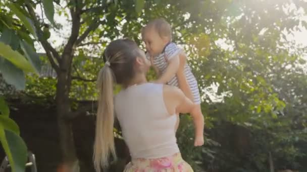Felice donna allegra sollevare il suo bambino figlio sotto l'albero a frutteto — Video Stock