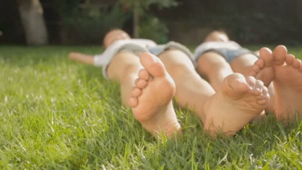 Dolly výstřel dvou přátel nohou ležící na trávě v parku — Stock video