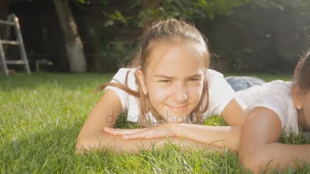 Dolly schot van twee leuke meisjes liggen op gras in achtertuin — Stockvideo