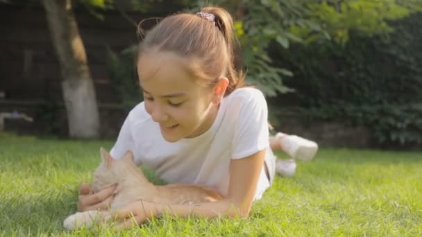 Porträt eines lächelnden Teenagers, der mit seinem Kätzchen im Gras liegt — Stockvideo