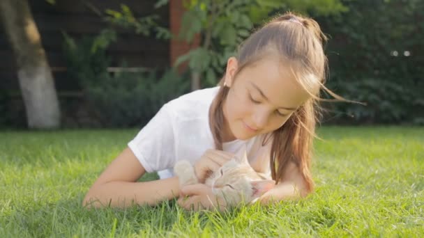 Porträt eines süßen Mädchens, das mit Kätzchen im Hinterhof auf dem Boden liegt — Stockvideo