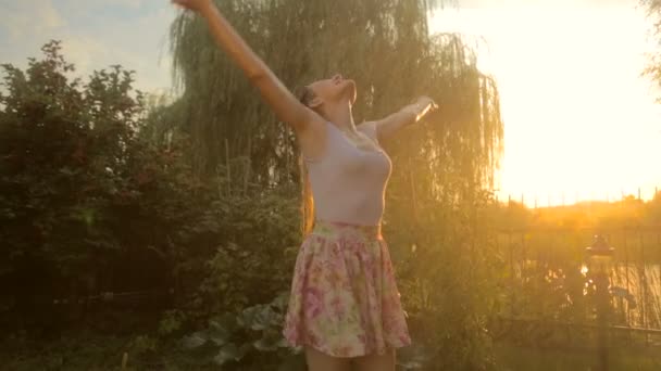 Mujer alegre riendo disfrutando de la lluvia de verano en el jardín al atardecer — Vídeos de Stock