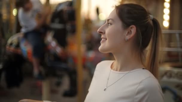Portret van mooie lachende vrouw in attractiepark bij avond — Stockvideo