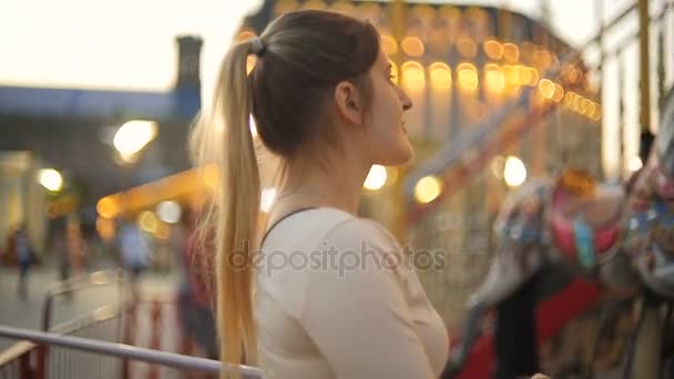 Close-up van mooie elegante vrouw kijken merry-go-round carrousel bij avond — Stockvideo