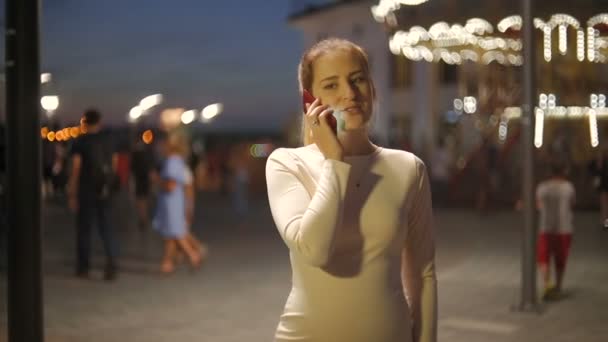 Porträt einer schönen lächelnden Frau, die nachts auf der Straße telefoniert — Stockvideo