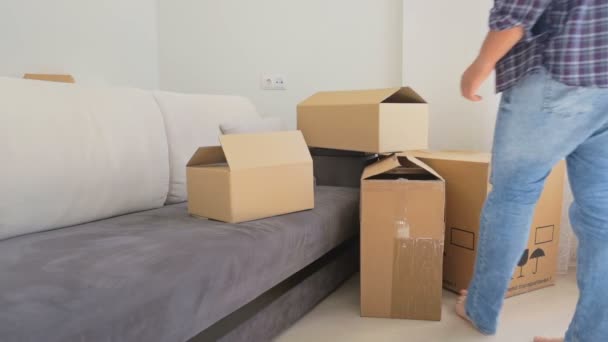 Familia joven que se muda de su antiguo apartamento y lleva cajas de la habitación — Vídeo de stock