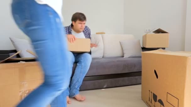 Casal jovem está cansado depois de se mudar em sua nova casa e descansar no sofá — Vídeo de Stock