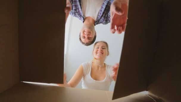 Vue de l'intérieur de la boîte en carton comme jeune couple souriant l'ouvrant — Video