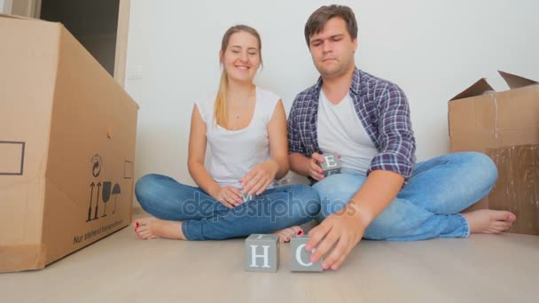 Felice giovane coppia che fa parola a casa da blocchi di legno — Video Stock