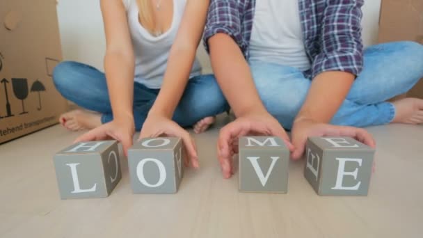 Primer plano de la familia joven haciendo palabras Casa y el amor en bloques de madera de juguete — Vídeos de Stock