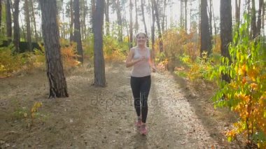 Ağır çekim bir güneşli sabah ormanda çalışan güzel gülümseyen kadın