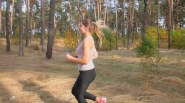 Orman yolu üzerinde çalışan active gülümseyen kadın yan görünümü ağır çekim görüntüleri