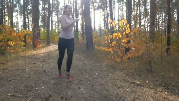 Медленный кадр счастливой улыбающейся женщины бегущей в лесу, чтобы сбросить вес — стоковое видео