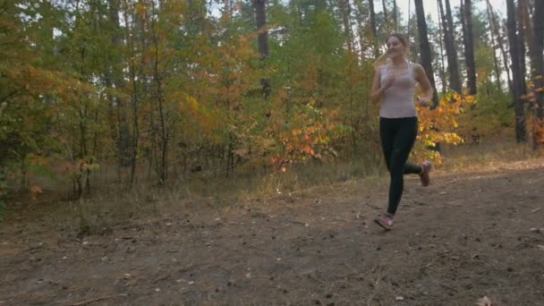 Mouvement lent de belle jeune femme souriante jogging en forêt le soir — Video