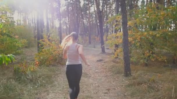 Lento tiro em movimento da bela jovem que se exercita na floresta de manhã — Vídeo de Stock