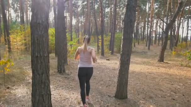 Vista trasera de cámara lenta de la joven corriendo rápido en el bosque — Vídeos de Stock