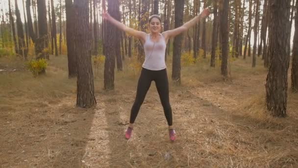 Movimiento lento de la mujer joven saltando y haciendo ejercicio en el bosque — Vídeos de Stock
