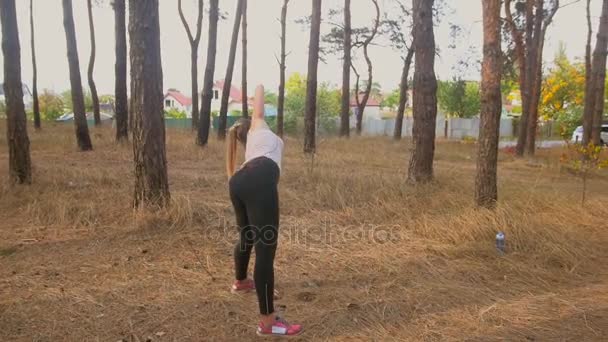 Zeitlupenaufnahme einer sexy jungen Frau, die sich im Wald aufwärmt und trainiert — Stockvideo