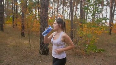 Orman ve içme suyu şişeden çalışan güzel ince kadın ağır çekim görüntüleri