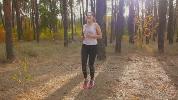 Tiro de movimento lento da jovem mulher aquecendo músculos e corpo antes de correr na floresta — Vídeo de Stock